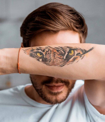 Men's feather tattoo combined with a design of a tiger inked on a forearm