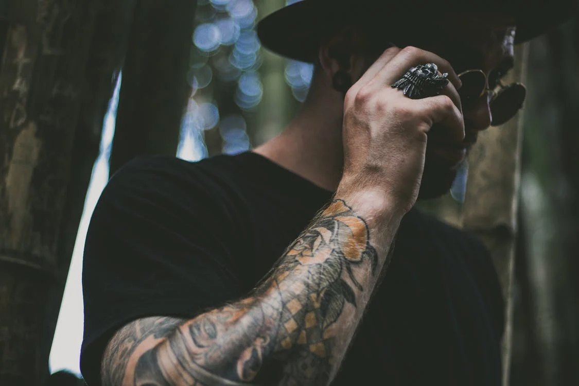 A man with a tattoo on his arm and a skull ring