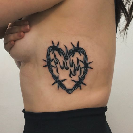 Barbed wire heart tattoo with an outline of a flame inside of it