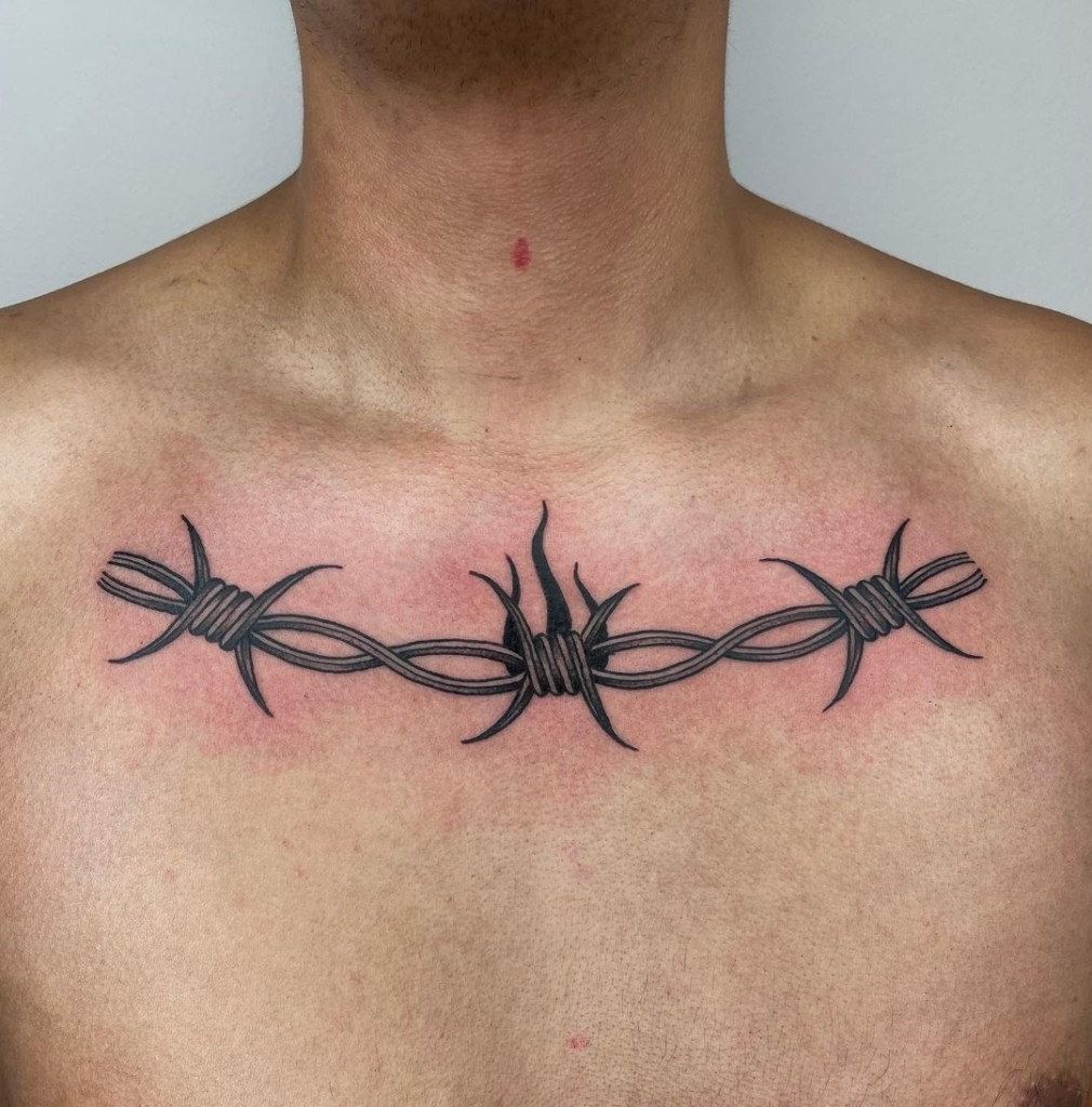 Black barbed wire surrounding smile inked on a calf