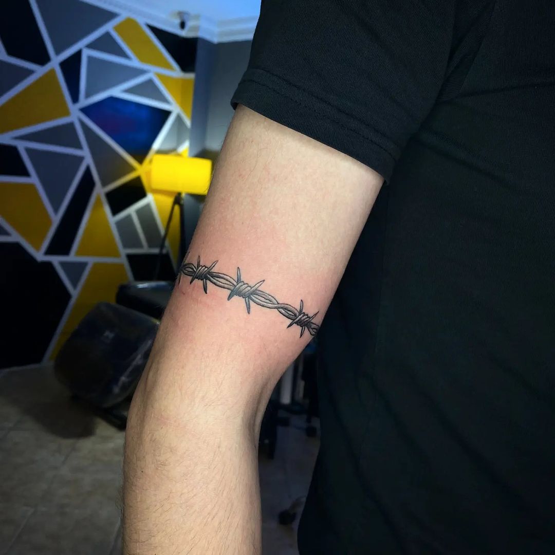 A classic black barbed wire tattoo on a bicep