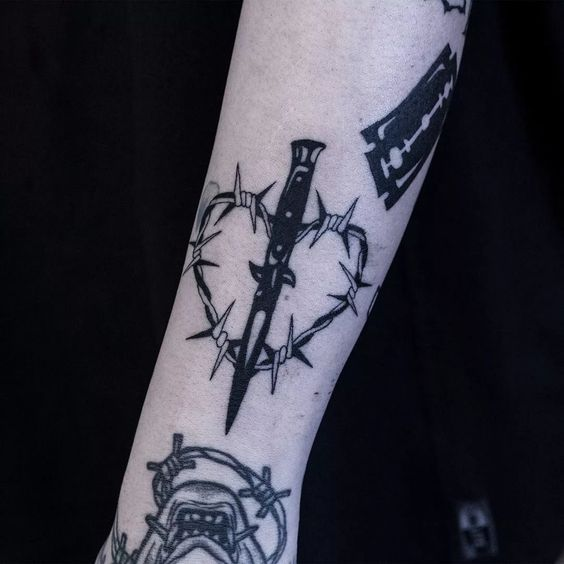 The barbed wire tattoo in the form of a heart combined with a knife design