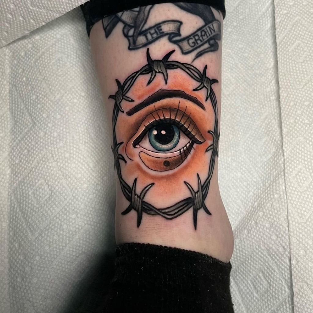 Barbed wire surrounding an eye inked on the ankle