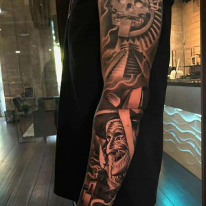 Man with Aztec sleeve tattoo featuring realistic designs on the arm