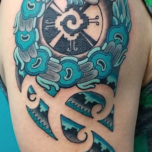 A feathered serpent, an Aztec symbol, inked in blue tones on the arm