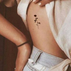 Minimalistic black rose tattoo on the ribs