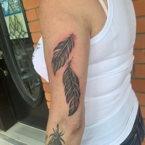 Two feathers inked on a woman's arm