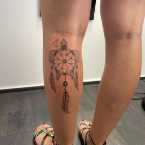 The dreamcatcher with feathers inked on the calf