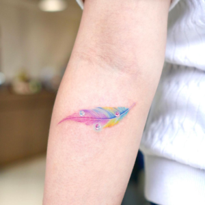 Small and colorful feather tattoo on the arm
