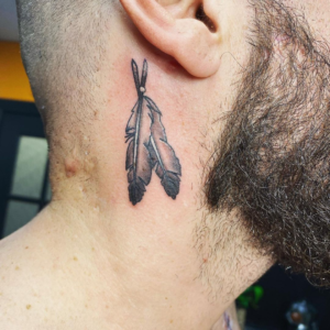 Two minimalistic feathers inked on the head